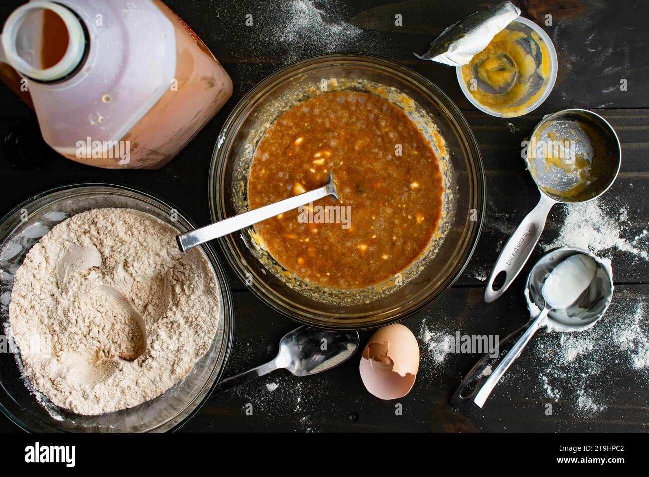 Mischen von feuchten Zutaten für gebackene Apfelwein-Donuts: Apfelsauce, griechischer Joghurt und andere Zutaten in einer Glasrührschüssel Stockfoto