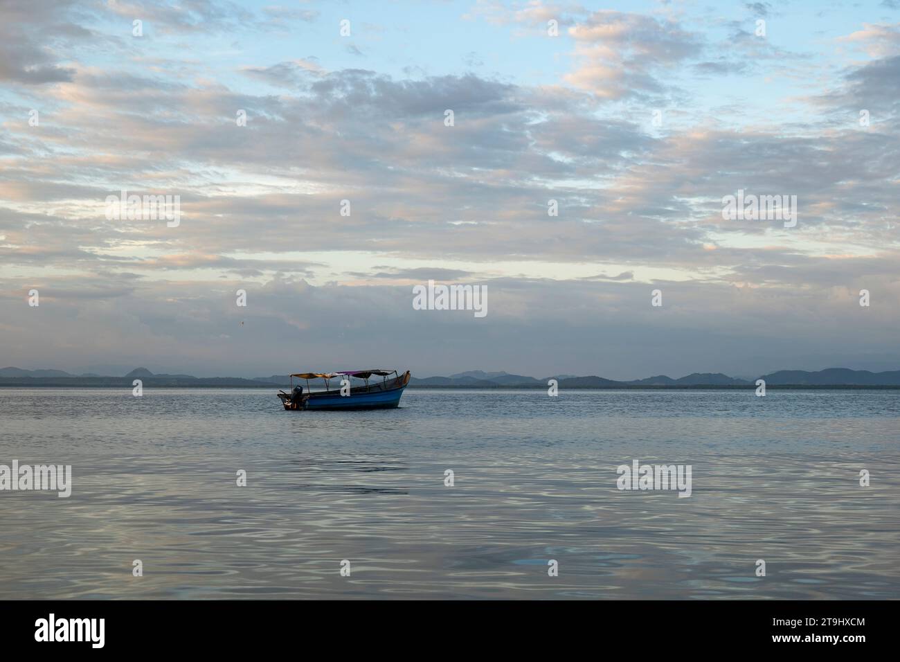 San Salvador, San Salvador, El Salvador – 30. Oktober 2022: Kleines Boot auf einem ruhigen Ozean vor einer Küste, die von Afar aus mit einem Vulkanberg gesehen wird Stockfoto