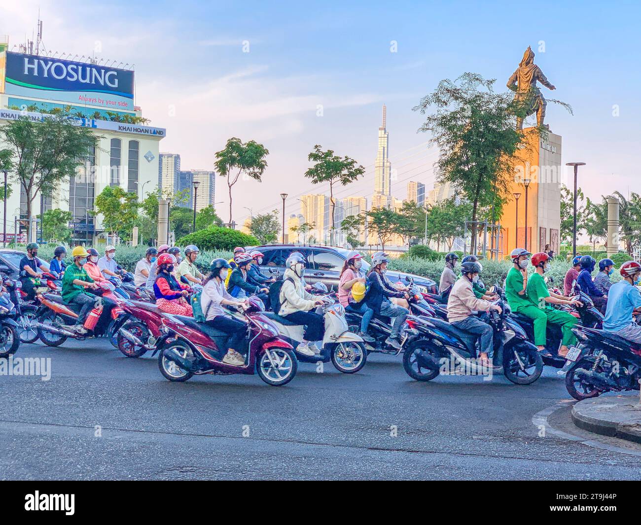 Vietnam, Ho Chi Minh Motorradverkehr in der Rush Hour. Tran Hung Dao Statue, Militärheld aus dem 13. Jahrhundert im Hintergrund. Stockfoto