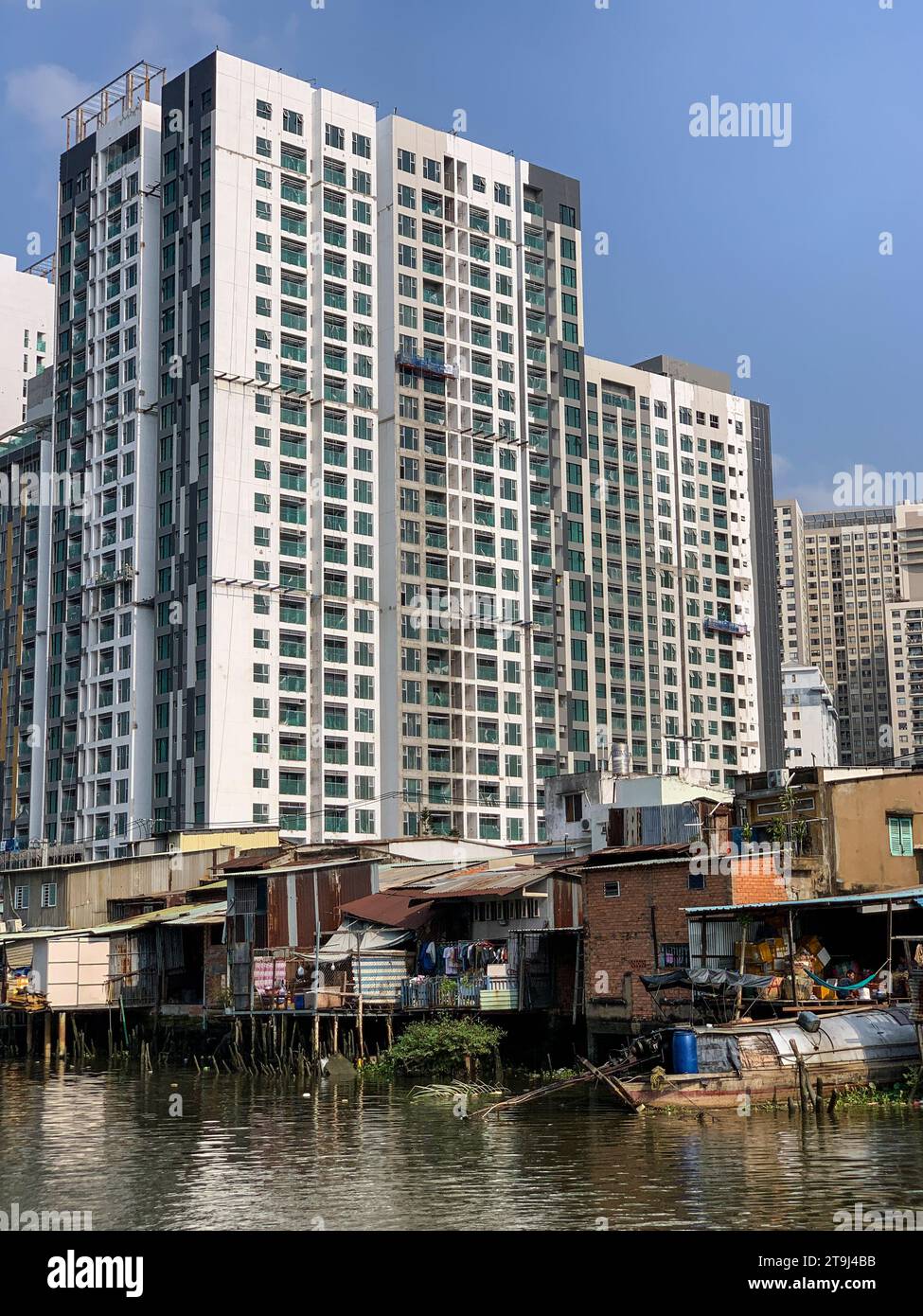 Ho Chi Minh, Vietnam. Nebeneinander von Hochhauswohnungen und armen Wohnhäusern am Fluss Saigon. Stockfoto