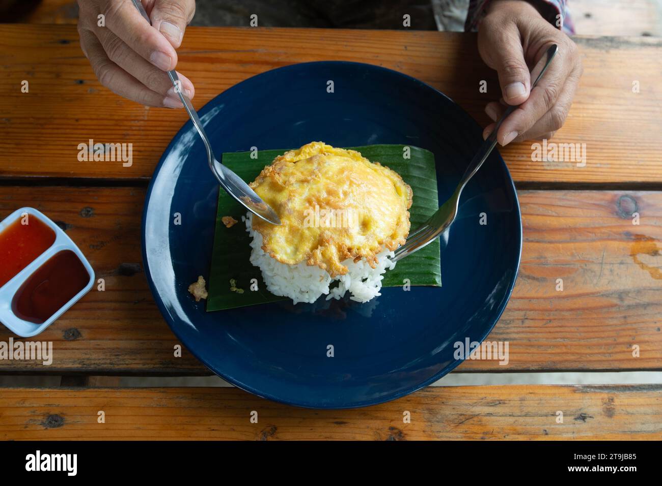 Ein Foto von oben zeigt, dass jemand thailändischen Omelettenreis isst, der so einfach ist wie Fast Food in Thailand. Stockfoto