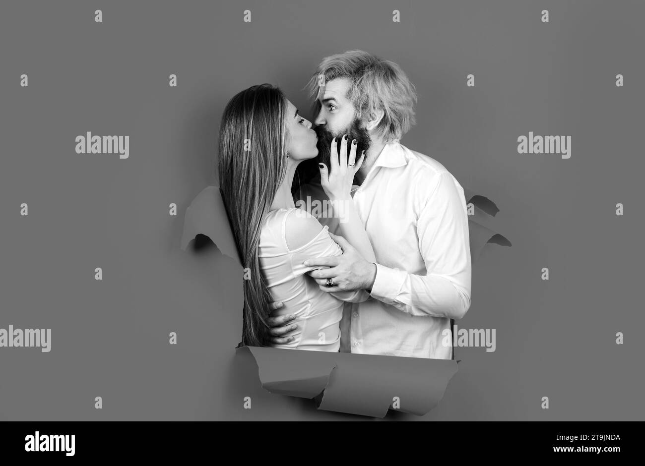 Paar in Loch Papier. Rabatt und Verkauf. Geküsste Paar bärtige Mann und glückliche Frau machen Loch in Papier Kuss durch Loch. Werbetafel, blau Stockfoto