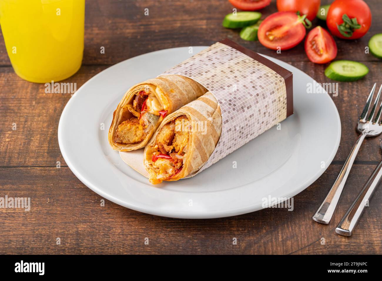 Hähnchenwicklung mit Gemüse auf einer weißen Porzellanplatte auf einem Holztisch Stockfoto