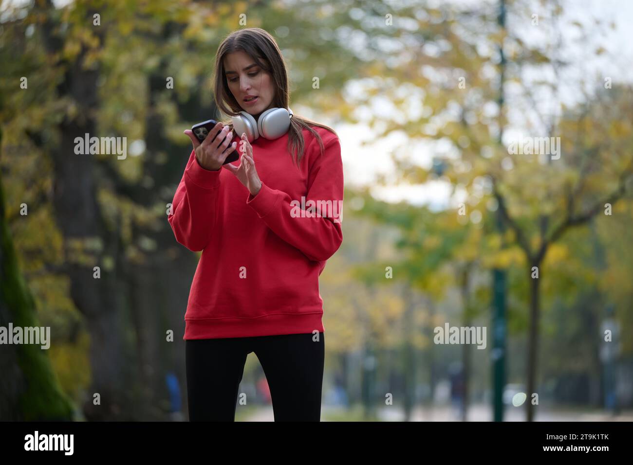 Sportliche Frau überprüft das Smartphone, bevor sie einige Übungen macht, hört Musik aus einer Playlist Stockfoto