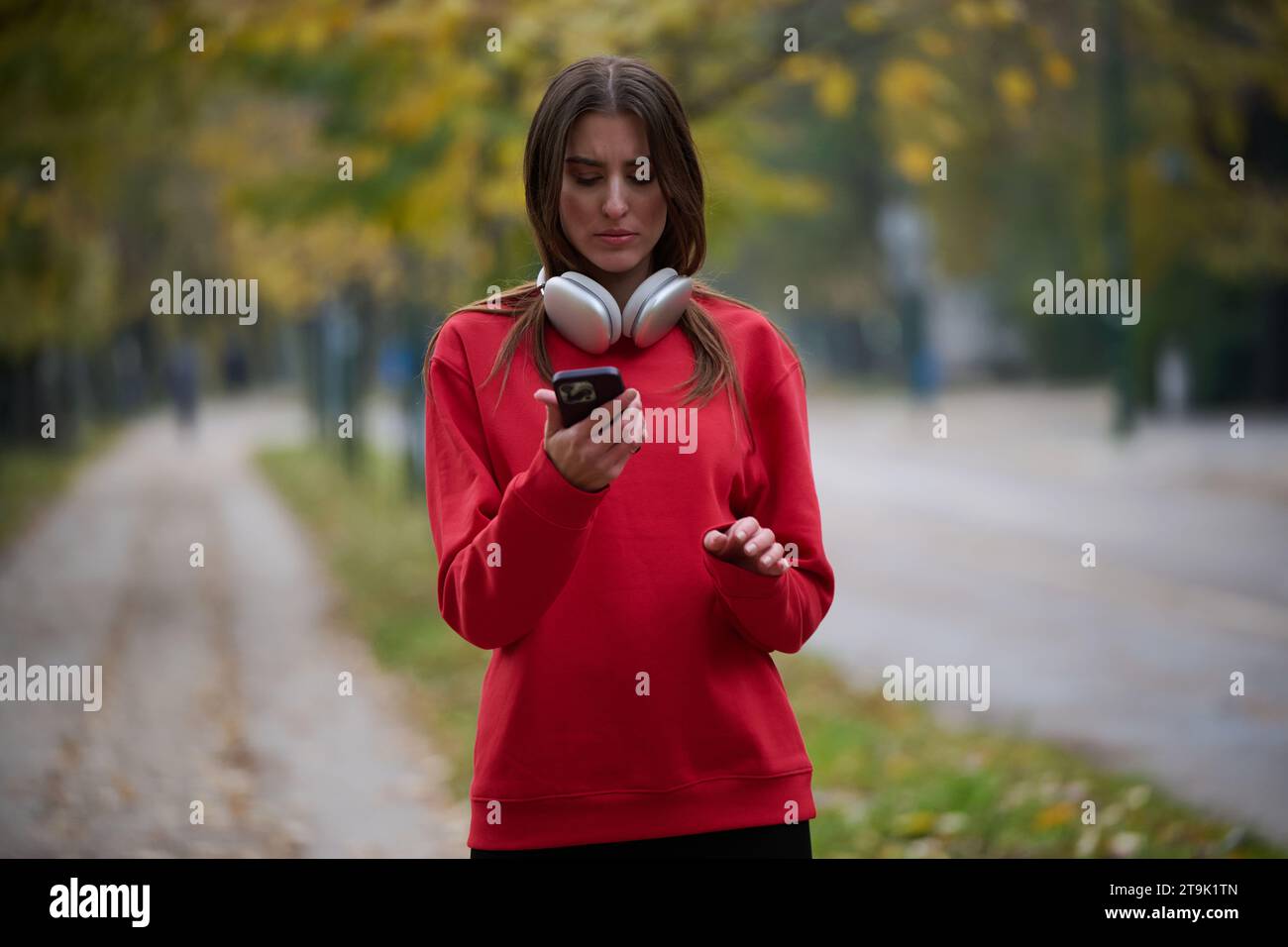 Sportliche Frau überprüft das Smartphone, bevor sie einige Übungen macht, hört Musik aus einer Playlist Stockfoto