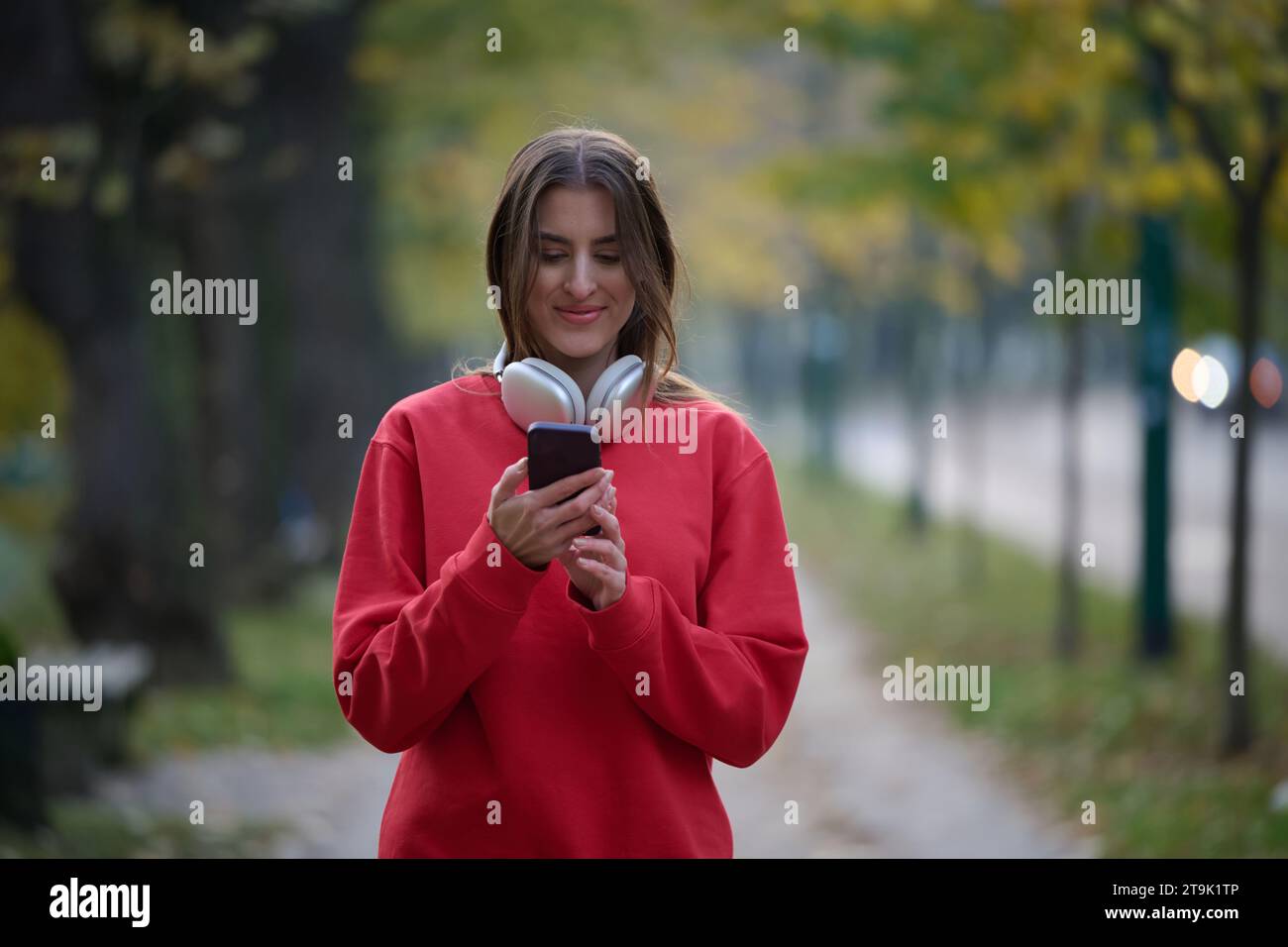 Sportliche Frau überprüft das Smartphone, bevor sie einige Übungen macht, hört Musik aus einer Playlist Stockfoto