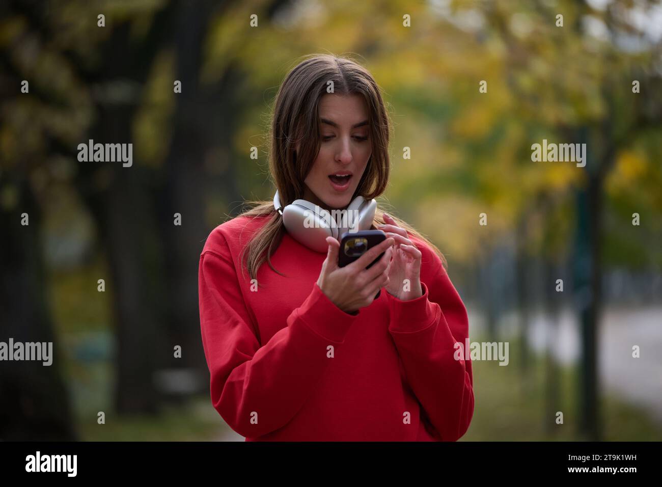 Sportliche Frau überprüft das Smartphone, bevor sie einige Übungen macht, hört Musik aus einer Playlist Stockfoto