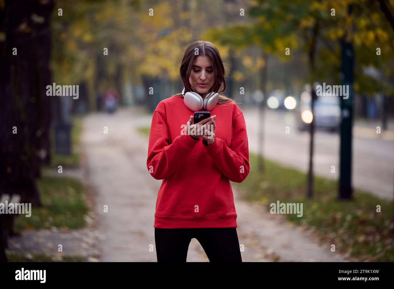 Sportliche Frau überprüft das Smartphone, bevor sie einige Übungen macht, hört Musik aus einer Playlist Stockfoto