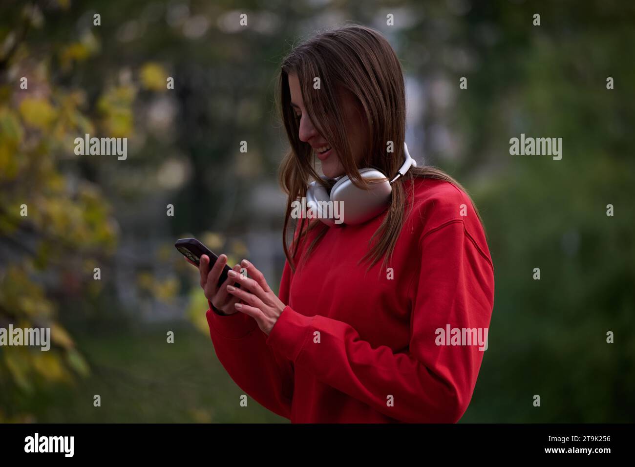 Sportliche Frau überprüft das Smartphone, bevor sie einige Übungen macht, hört Musik aus einer Playlist Stockfoto