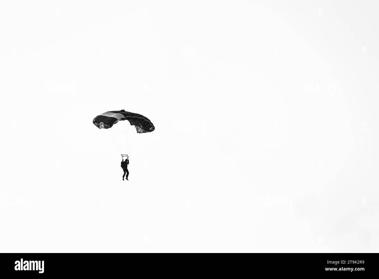 Abstraktes Minimalbild mit einem Fallschirmspringer auf weißem Hintergrund. Stockfoto