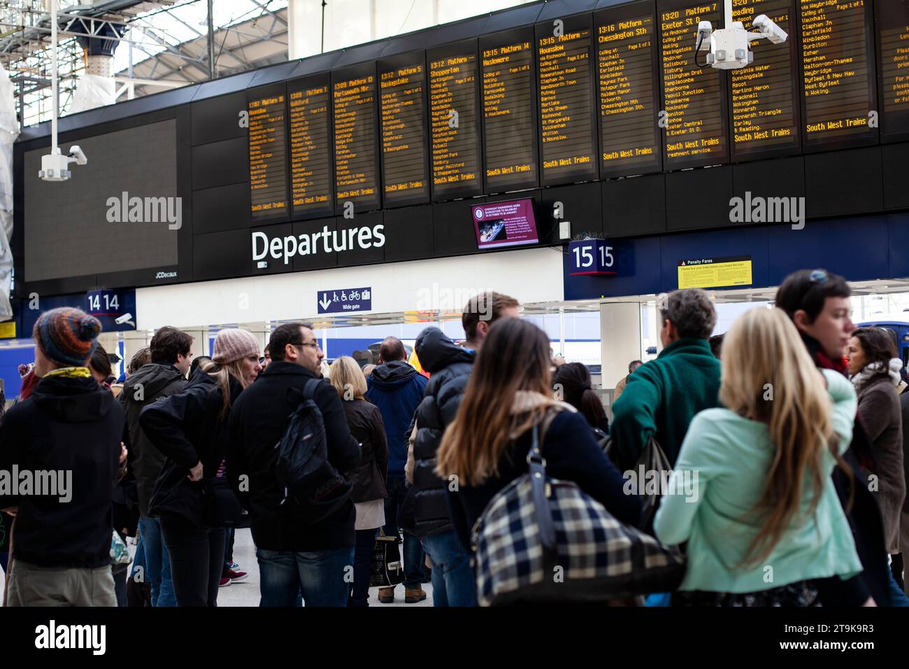 Gruppe von Personen, die die elektronischen Abfahrten am Bahnhof Paddington in London beobachten Stockfoto