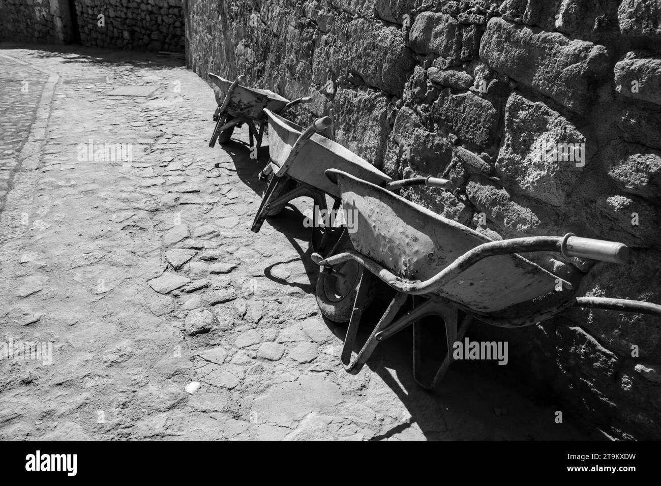 Drei Schubkarren, die auf eine Steinmauer in Spanien gelehnt sind Stockfoto