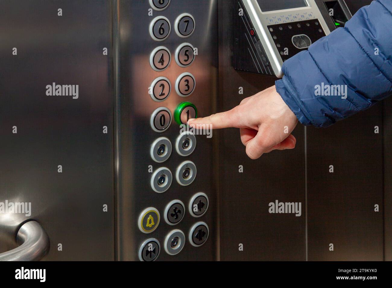 Ein Mann drückt im Fahrstuhl des Business Centers auf den Fußbodenknopf. Stockfoto