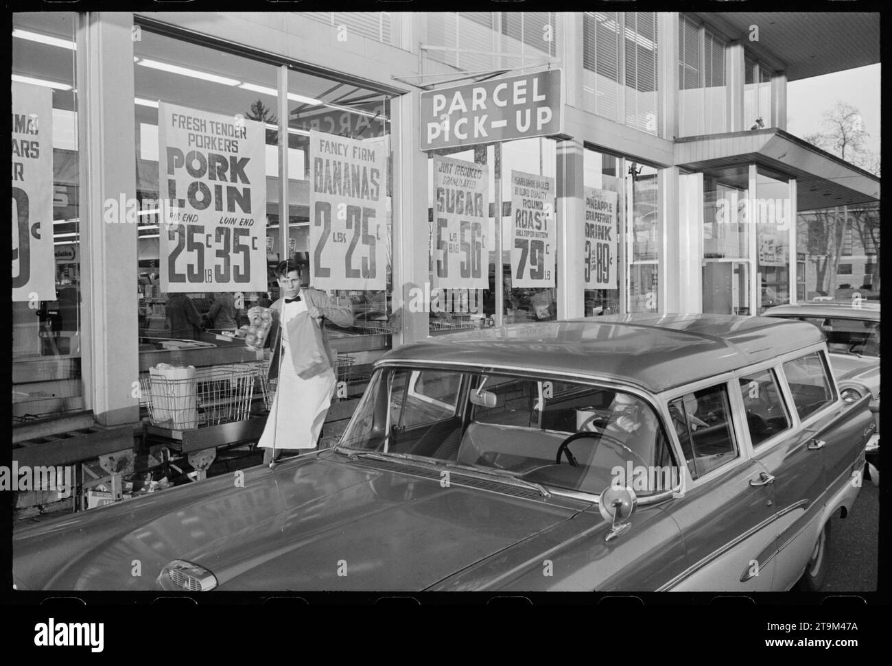 Mitarbeiter des Grand Union Supermarkt-Geschäfts, der einer Person in einem Auto an einer Drive-Thru-Pick-up-Linie Lebensmittel-Taschen übergibt, New Jersey, Januar 1960. (Foto: Thomas O'Halloran/US News and World Report Magazine Collection) Stockfoto