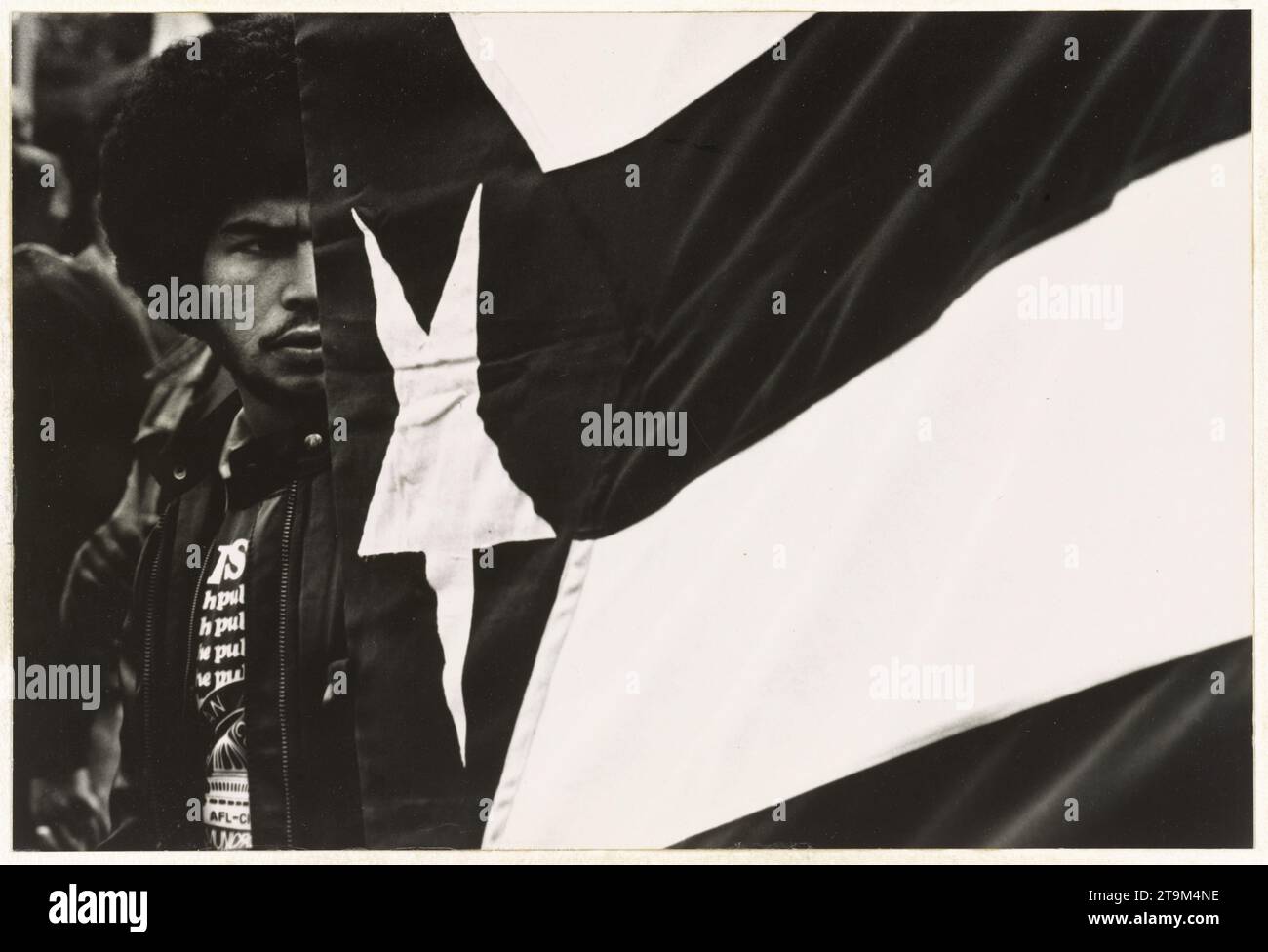 Junger Mann, der hinter einer Puerto-ricanischen Flagge steht, kein Ort, um 1970. (Foto: Frank Espada) Stockfoto