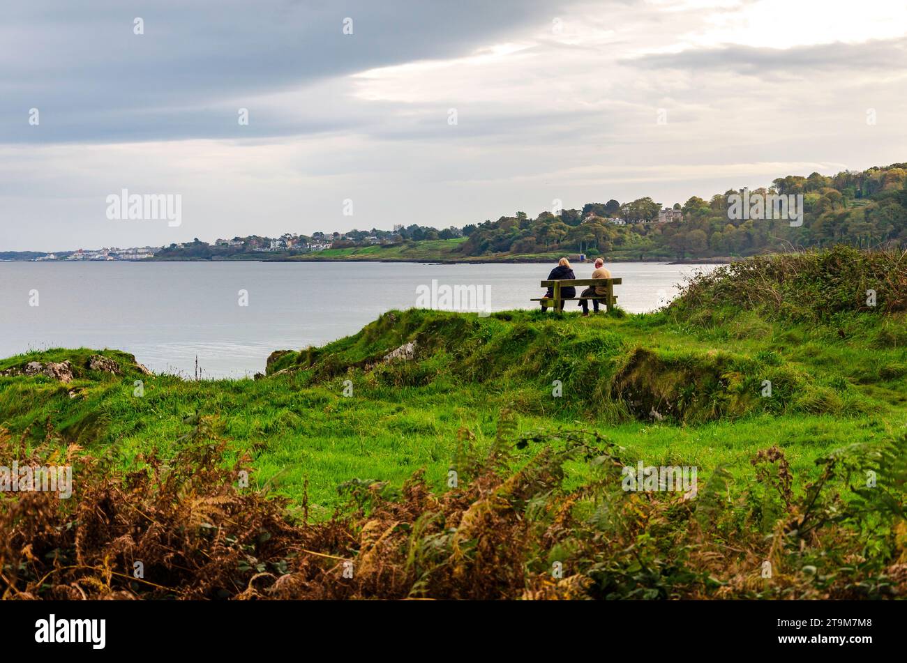 Crawfordsburn, County Down, Nordirland 10. Oktober 2023 – zwei Personen sitzen auf einer Bank und bewundern die Aussicht in der Nähe von Crawfordsburn Stockfoto