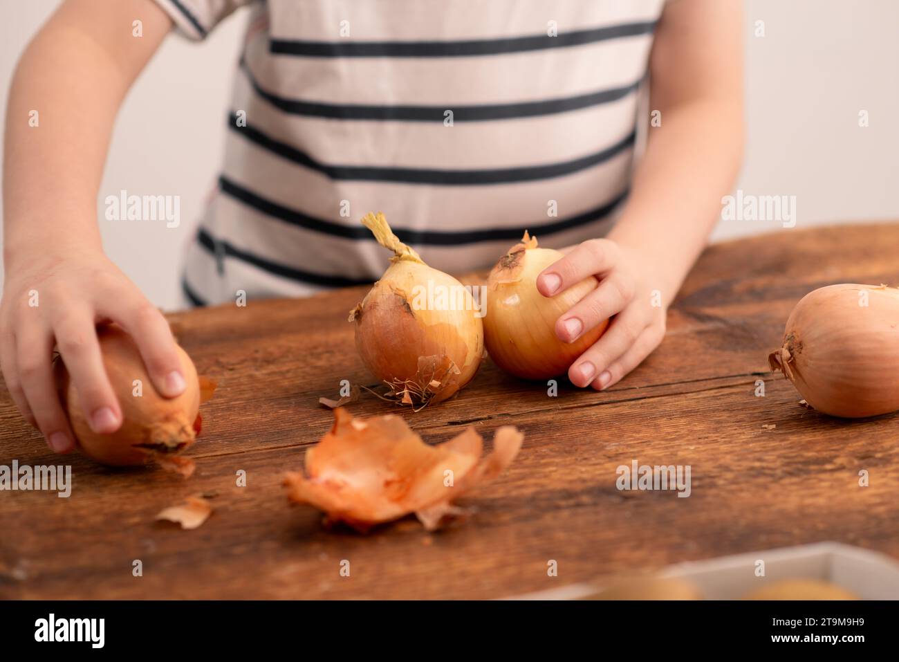 Zwiebelelegantheit: Ein Kind präsentiert eine ganze Zwiebelschale, die den Nährwert und die Freude symbolisiert, diese Grundnahrungsmittel in die Mahlzeiten zu integrieren Stockfoto