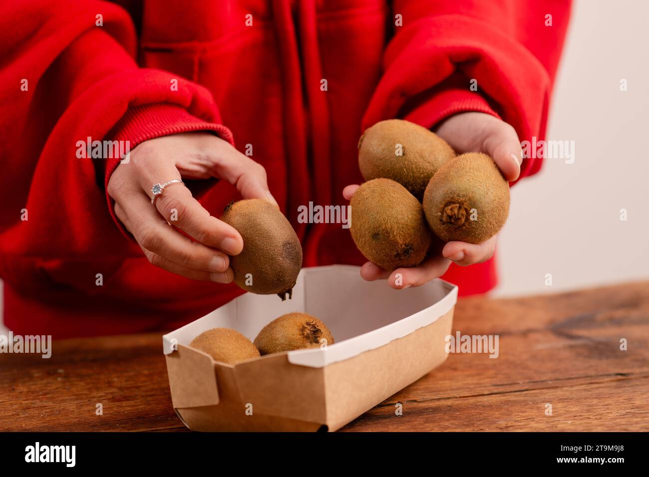 Frauenhände halten ganze Kiwis und zeigen die Vorteile dieser Früchte, fördern Wellness und einen gesunden Lebensstil Stockfoto