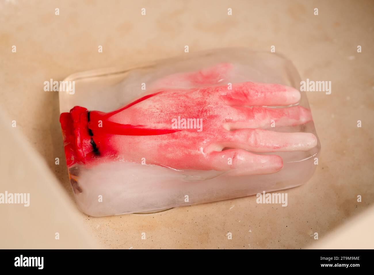 Eiskalter Horror: Ein konzeptionelles Horrorbild mit einer künstlichen menschlichen Hand, die in einem Eisblock eingefroren ist und eine unheimliche und spannende Atmosphäre schafft Stockfoto