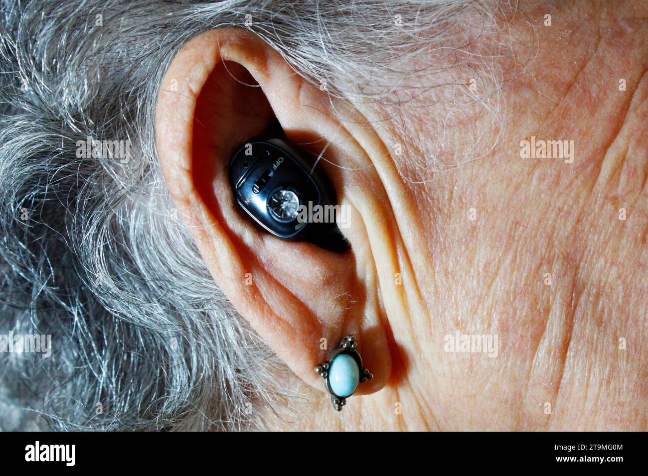 Ältere Erwachsene Frau mit Hörgerät zur Erhöhung ihrer Hörfähigkeit Stockfoto