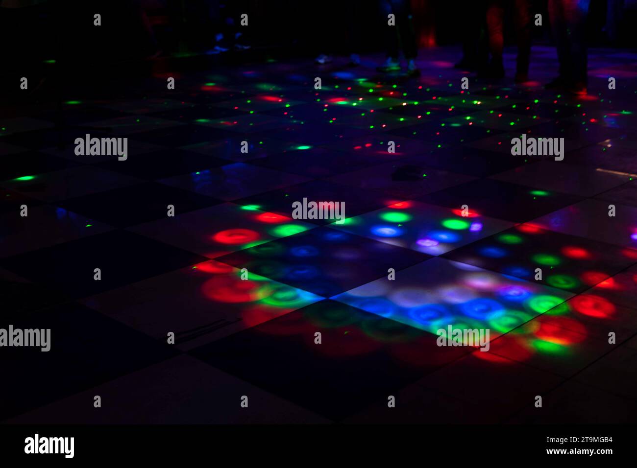 Disco im Club. Tanzfläche in farbigen Flecken. Leichte Musik im Club. Helle Beleuchtung auf dem Boden. Stockfoto