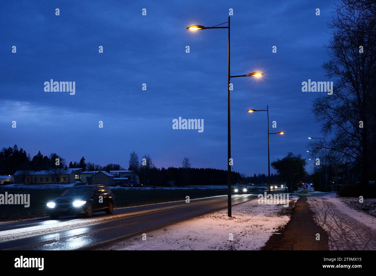Nachtverkehr von Autos auf der Straße in einer finnischen Kleinstadt im Winter Stockfoto