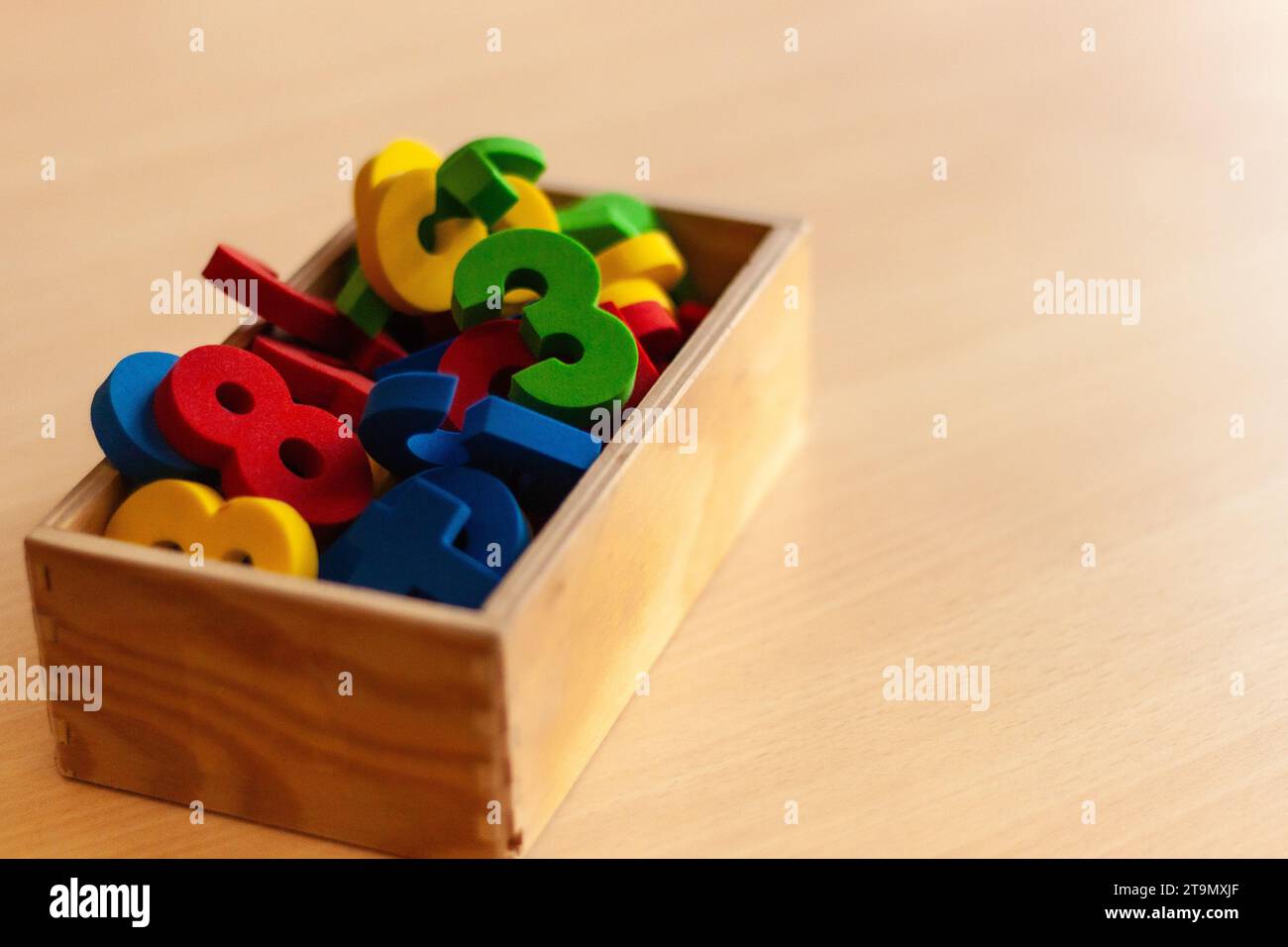 Holzkiste gefüllt mit bunten Zahlen, für Kinder, die lernen Stockfoto