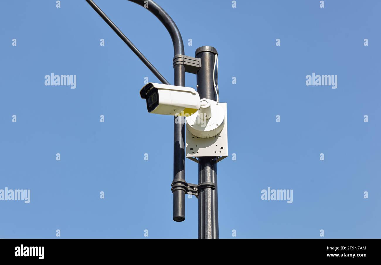 Überwachungskamerasicherheit am Pol. Moderne Überwachungskamera am Laternenpfosten auf einer Stadtstraße Stockfoto