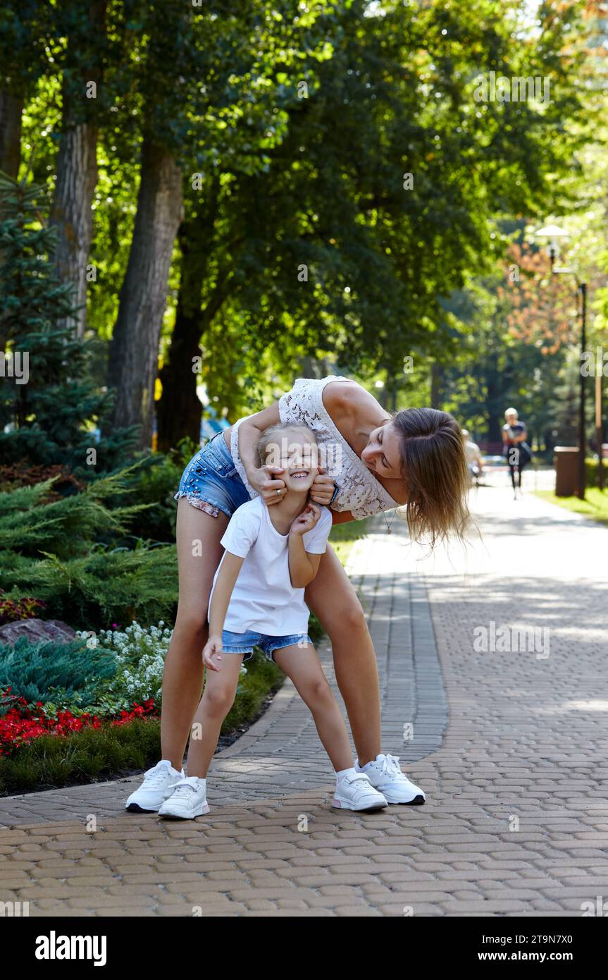 Mutter und Tochter gehen im Sommerpark spazieren. Kindheit, Freizeit und Menschen Konzept - glückliche Familie, Ruhe in der Natur und haben eine gute Zeit Stockfoto