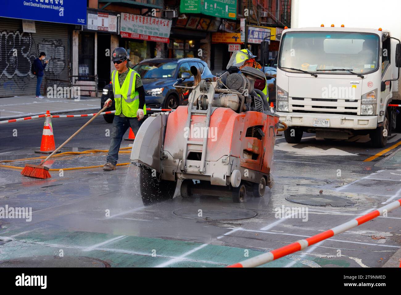 Ein Bauteam betreibt eine selbstfahrende Husqvarna FS 7000, die hinter einer Flachsäge auf einer Straße in New York City läuft. Stockfoto