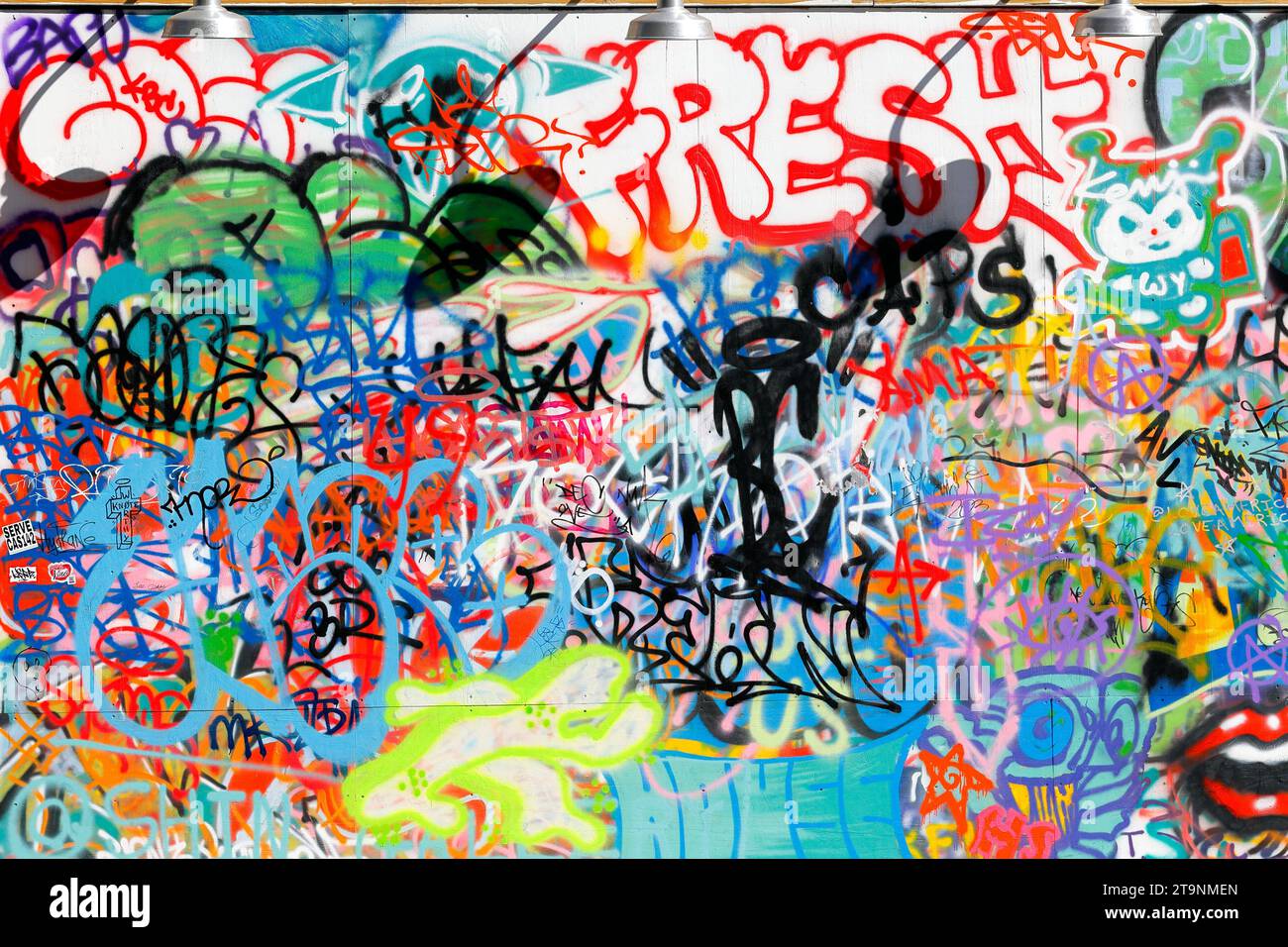 Helle, farbenfrohe Graffiti, Tagging, Vandalismus und antisoziales Verhalten an einer Stadtmauer. Stockfoto