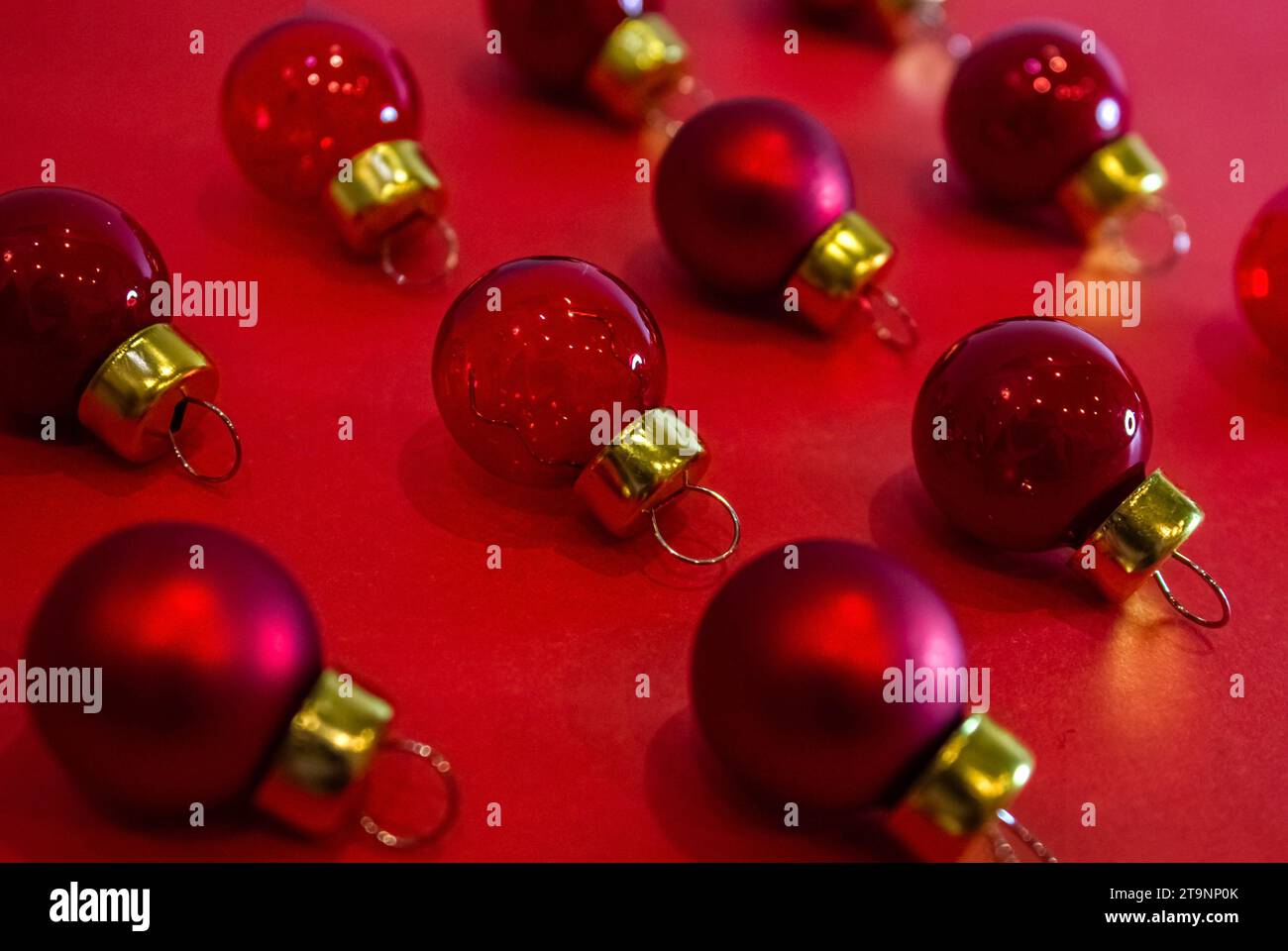 Christmas Minimal Pattern - Rote Weihnachtskugeln auf rotem Hintergrund. Horizontale Zusammensetzung. Flache Lage, Draufsicht. Stockfoto