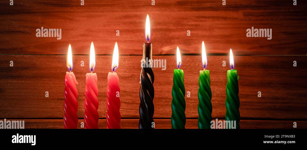 Happy Kwanzaa. Afroamerikanischer Urlaub. Sieben brennende Kerzen, rot, schwarz und grün, in Kinara-Kerzenleuchter. Symbole des afrikanischen Erbes. Bannerforma Stockfoto