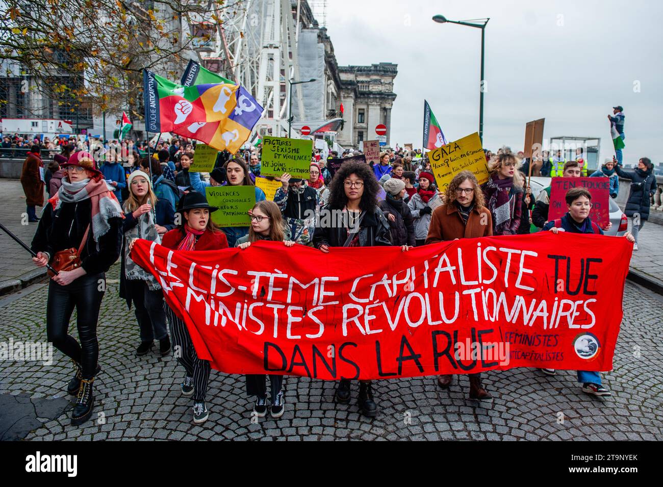 Während der Demonstration werden Demonstranten mit einem großen roten Banner gegen den Kapitalismus gesehen. Anlässlich des Internationalen Tages gegen Gewalt gegen Frauen fand auf Initiative von "Mirabal Belgium" (einer Gruppe mehrerer zivilgesellschaftlicher Verbände) in der belgischen Hauptstadt eine neue nationale Demonstration zur Bekämpfung von Gewalt gegen Frauen statt. Tausende von Menschen marschierten an diesem Tag, um ein deutliches Signal für die Beseitigung der Gewalt gegen Frauen zu setzen und die Zivilgesellschaft (Verbände und Bürger) dazu aufzurufen, ihre Ablehnung der "Machismo"-Gewalt zum Ausdruck zu bringen. Stockfoto