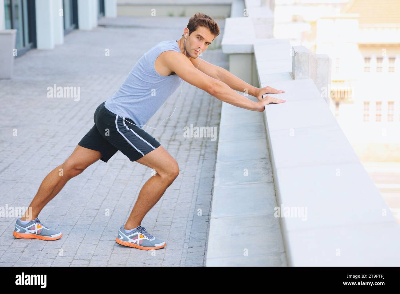 Mann, Porträt und Stretchkörper auf dem Balkon in der Stadt für Fitness, Workout oder Outdoor-Training. Aktive männliche Person beim Aufwärmen, Dehnen oder Vorbereitung Stockfoto