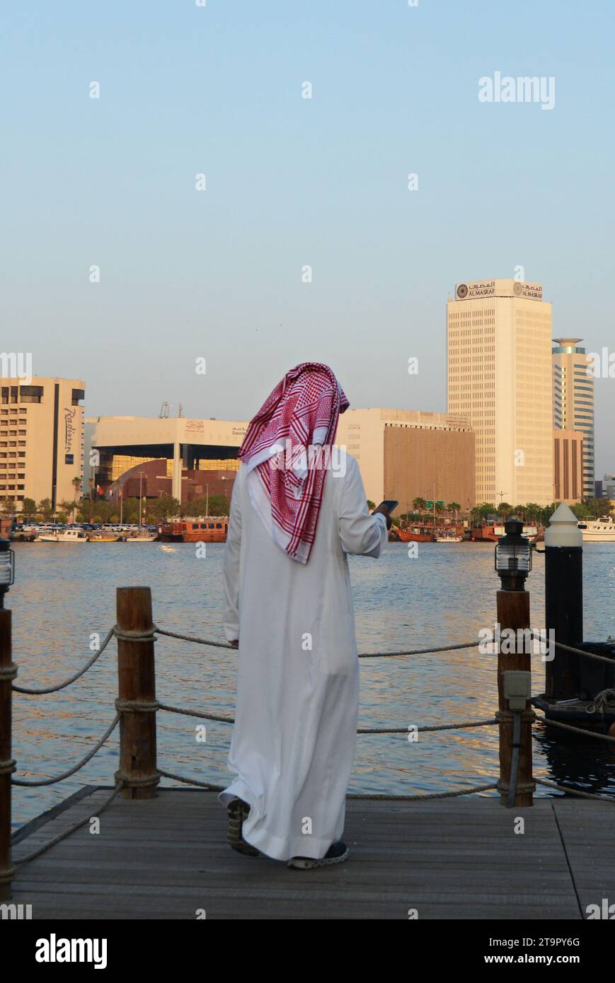 Ein saudischer Mann, der die Aussicht auf den Dubai Creek und Deira in Dubai, Vereinigte Arabische Emirate, genießt. Stockfoto