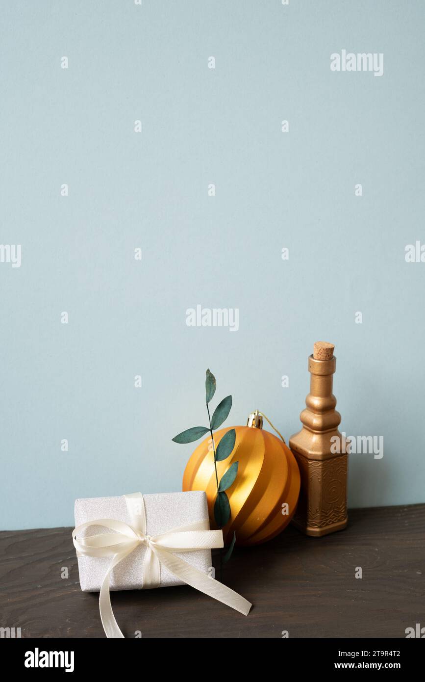 Weihnachtsdekoration Ornament goldene Kugel, Geschenkbox auf Holztisch. Blauer Wandhintergrund Stockfoto