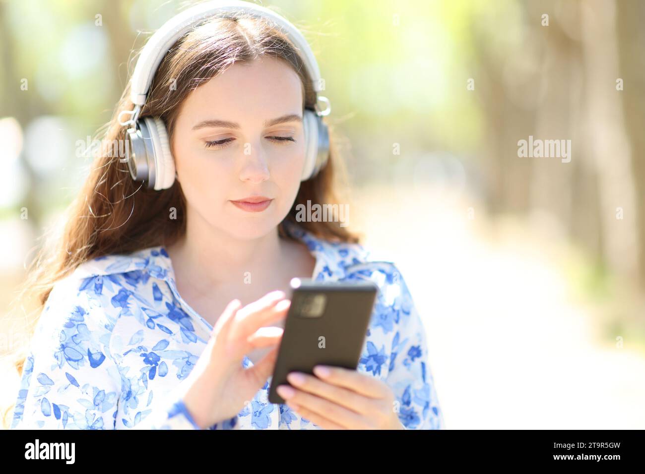 Frau, die Musik hört, läuft in einem Park an einem sonnigen Sommertag Stockfoto