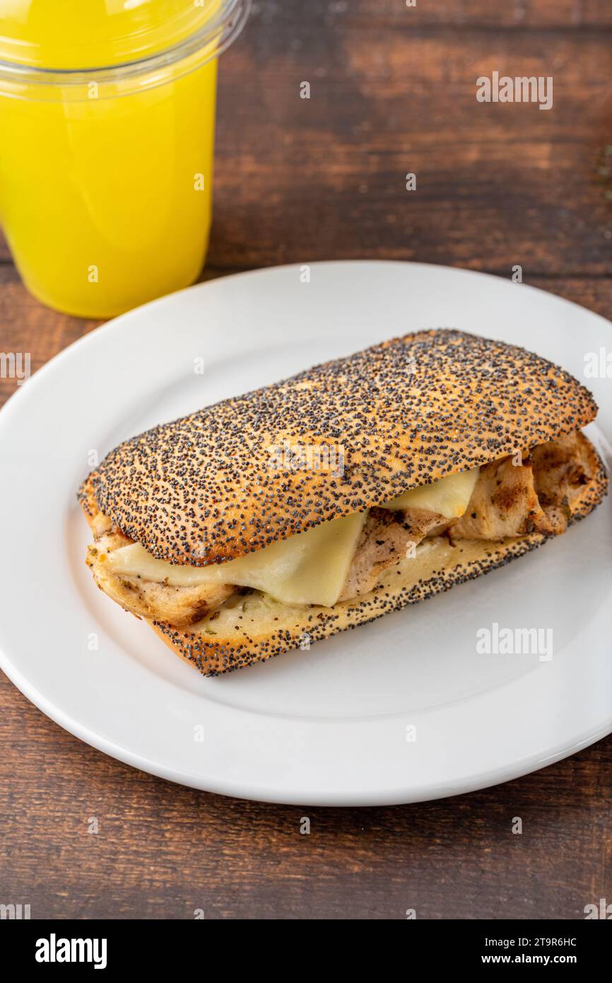 Sandwich mit Cheddar-Käse und Hühnchen auf weißem Porzellanteller auf Holztisch Stockfoto