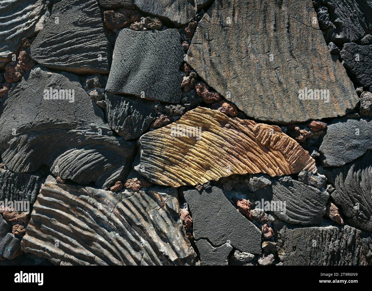 Steinmauer aus vulkanischem Gestein in verschiedenen Größen, Formen und Farbtönen. Vintage Wandkonstruktion aus Natursteinen. Stockfoto