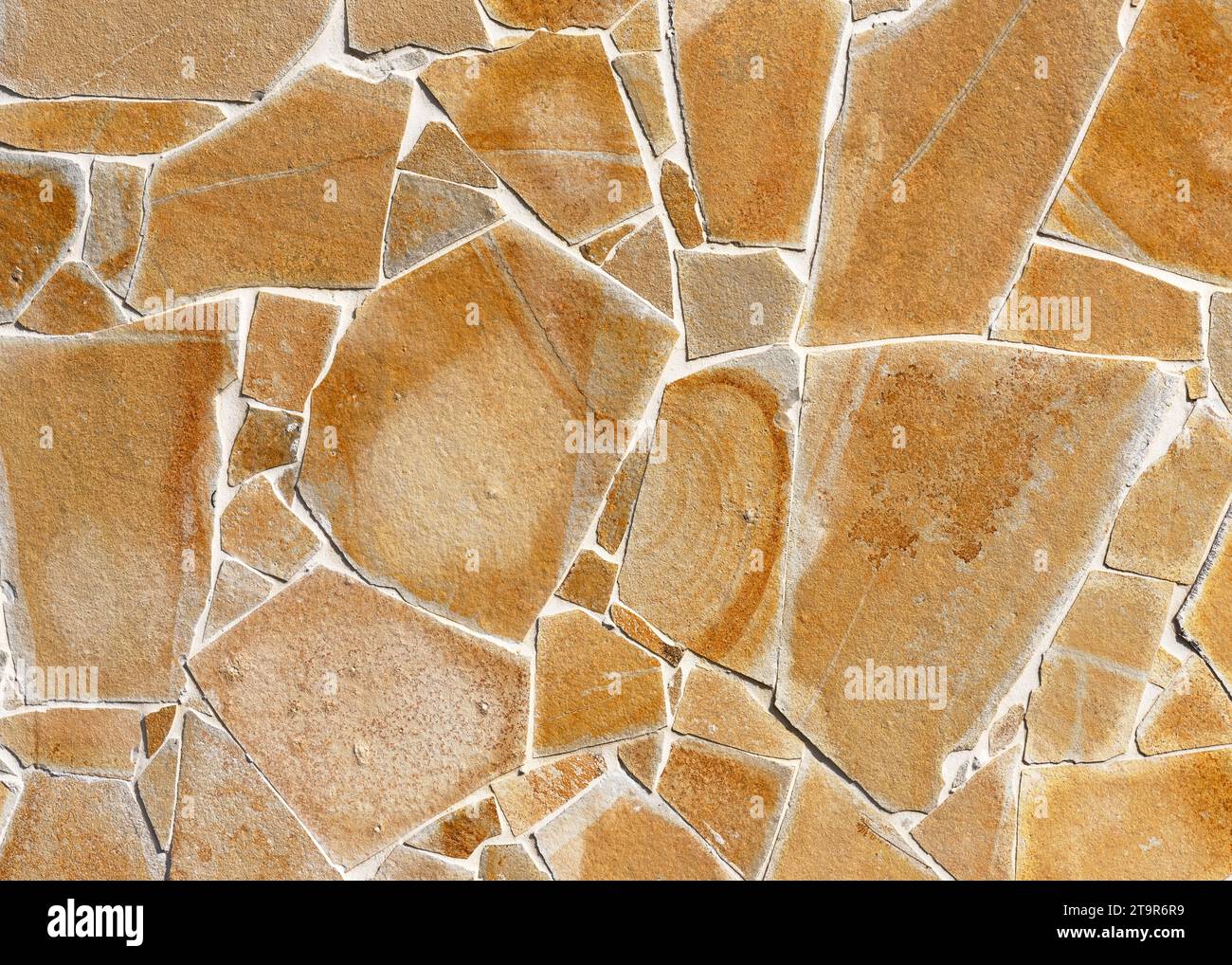 Beige und gelbe rustikale Mosaik Natursteinmauer aus kleinen Teilen. Vintage-Dekorationselemente. Abstraktes geometrisches Muster oder Hintergrund für Design Stockfoto