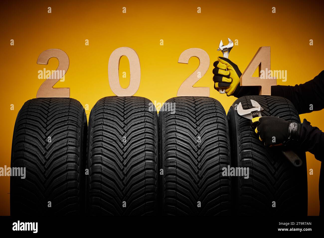 Winterreifen Servic, Hände des Mechanikers mit Schraubendreher und Text 2024 Happy New Year Hintergrund Stockfoto