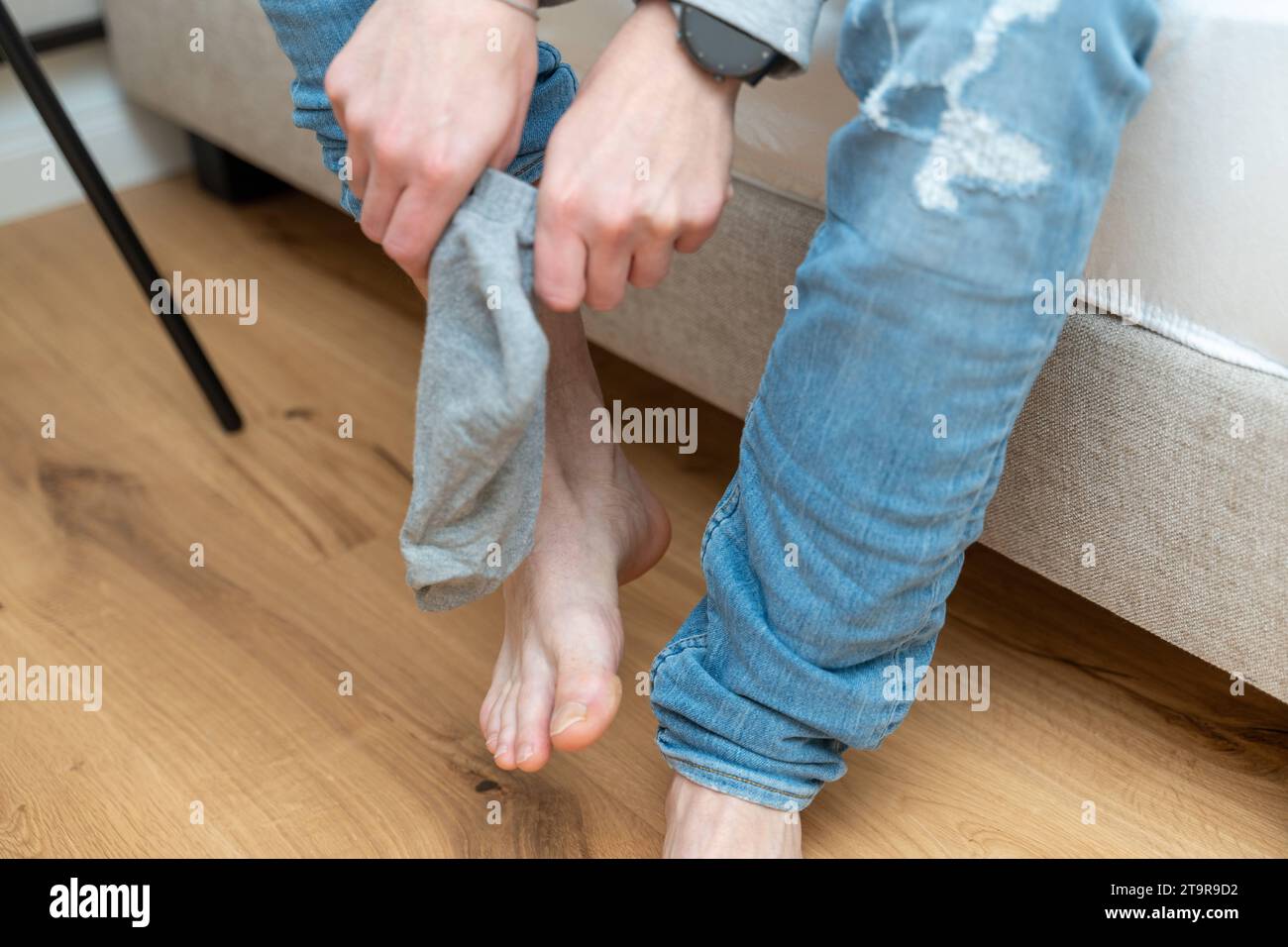Bayern, Deutschland - 26. November 2023: Ein junger Mann sitzt auf seinem Bett und zieht sich Socken über die Füße. Mann, der Socken anzieht *** ein junger Mann sitzt nach dem Aufstehen auf dem Bett und zieht sich über seine Füße Socken. Mann beim Socken Anziehen Credit: Imago/Alamy Live News Stockfoto