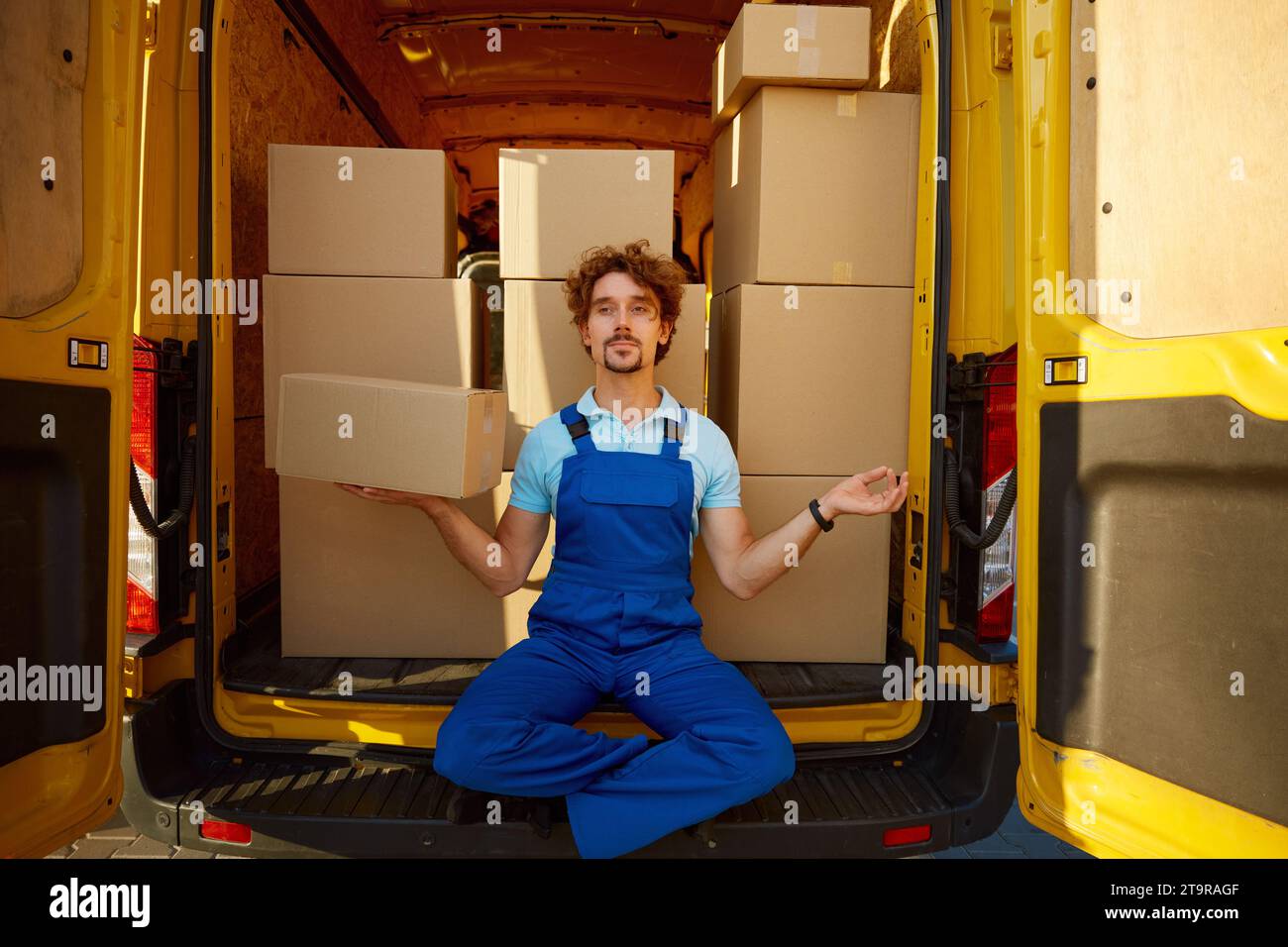 Der Kurier meditiert, um den Paketkasten in der Hand zu halten Stockfoto