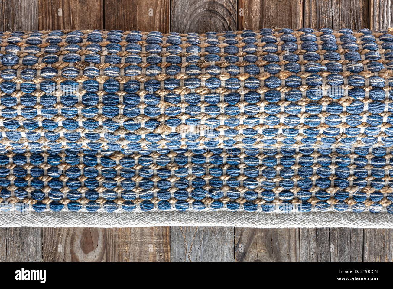 Handgewebter Teppich mit geometrischem Denim-Bereich auf Holzboden. Stockfoto