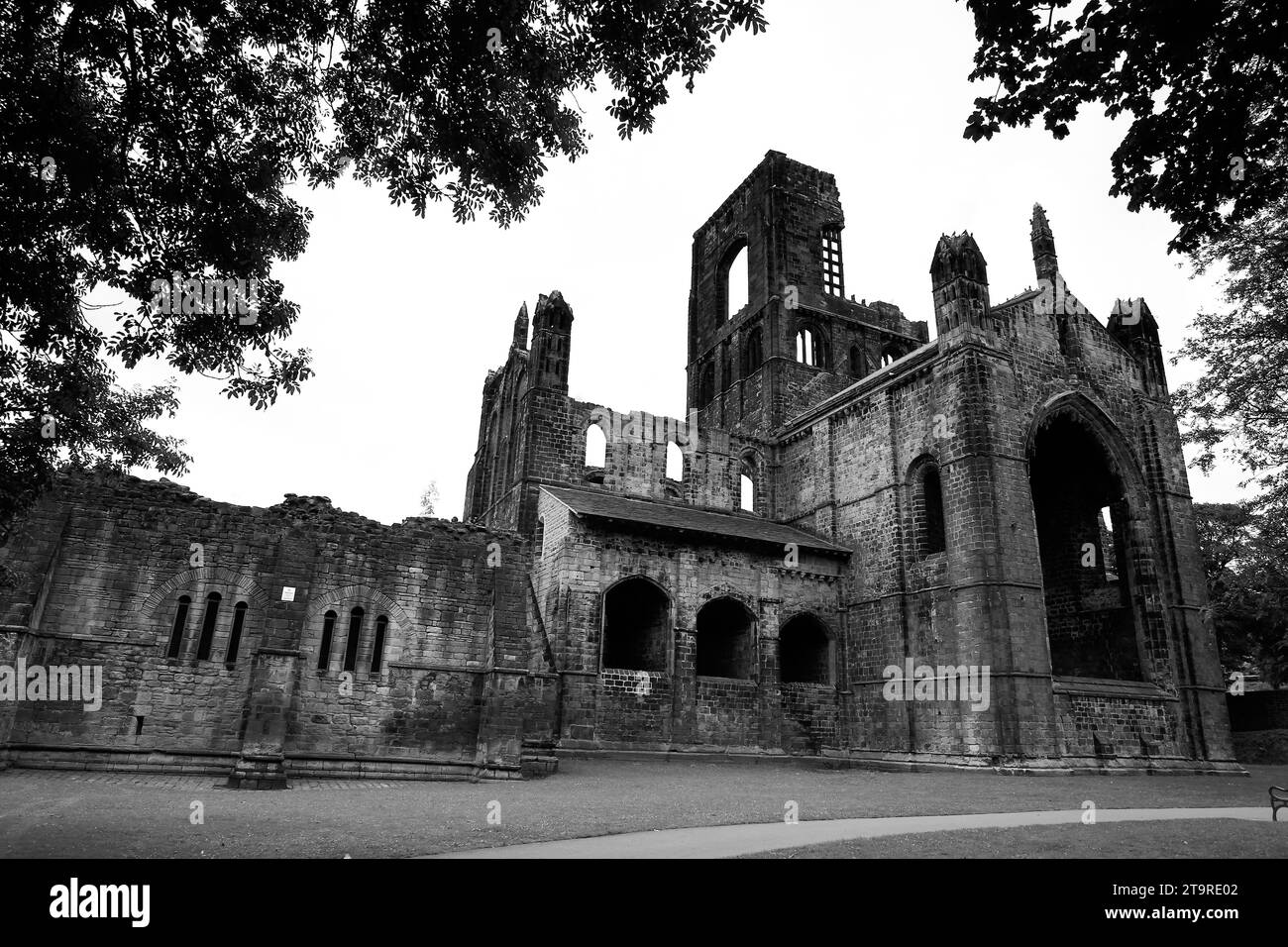 Eine allgemeine Schwarzweißansicht der Kirkstall Abbey, eingerahmt von Bäumen in Leeds, England. Stockfoto