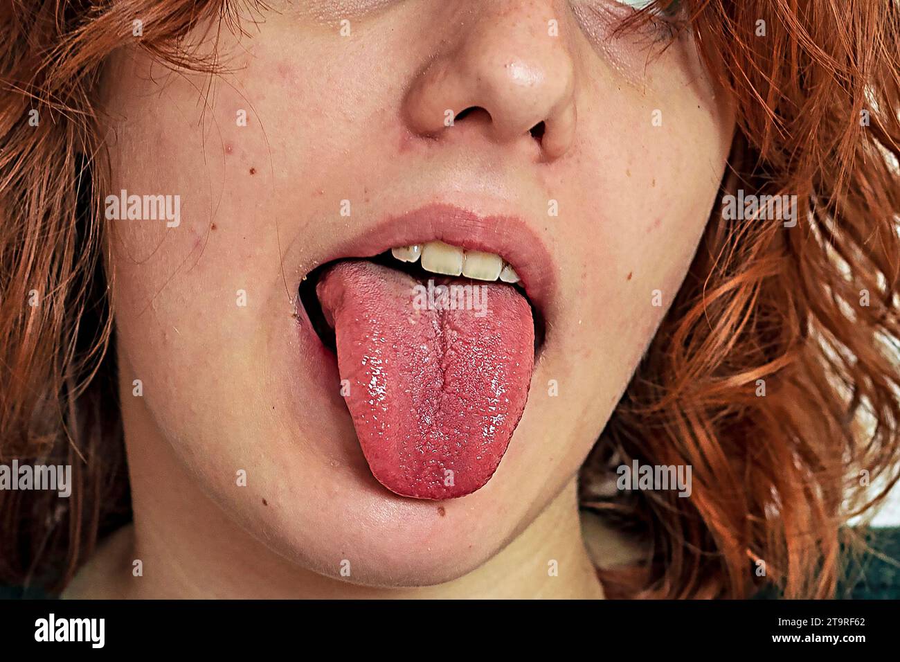 Stilvolles Teenager-Mädchen mit lockigen, kurzen Haaren, die ihrer Zunge rausragen Stockfoto