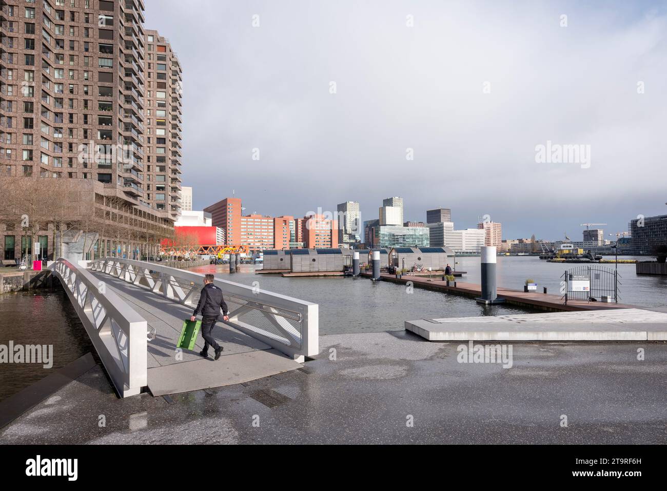 rotterdam, niederlande, 25. november 2023: Mann auf Brücke für Fußgänger in der Nähe von schwimmenden Kabinen in rijnhaven bei kop van zuid in der niederländischen Stadt rotterdam Stockfoto