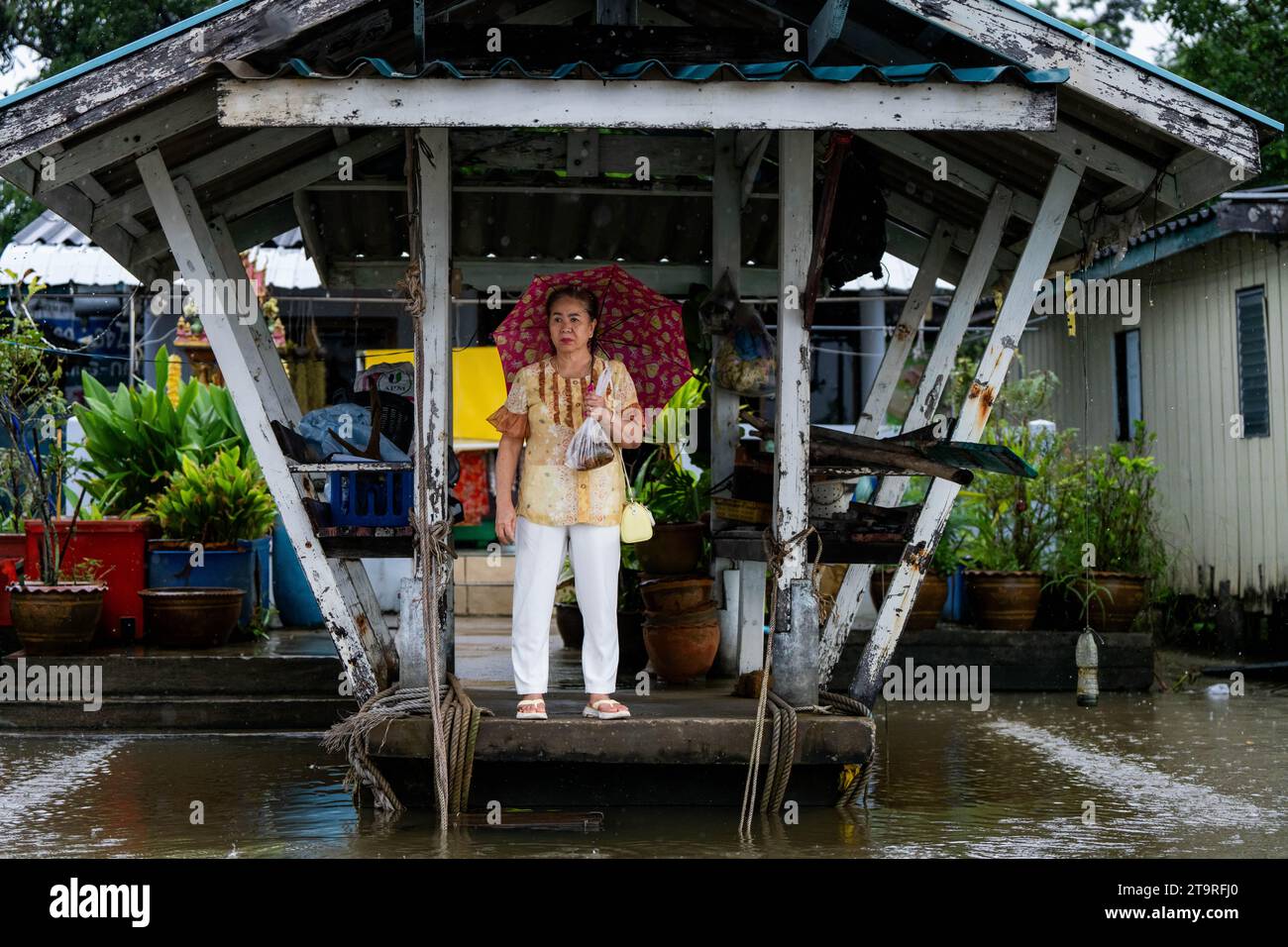 Surat Thani, Thailand. November 2023. Eine Frau wartet auf ein Boot, das sie von der Veranda abholt, während das Hochwasser aus dem Tapi River bei starken Regenfällen aufsteigt. In Surat Thani, Thailand, einem tropischen Gebiet, das während der Regenzeit im Süden zunehmend vom Klimawandel betroffen ist, finden starke Regenfälle und Überschwemmungen statt. (Foto: Matt Hunt/SOPA Images/SIPA USA) Credit: SIPA USA/Alamy Live News Stockfoto