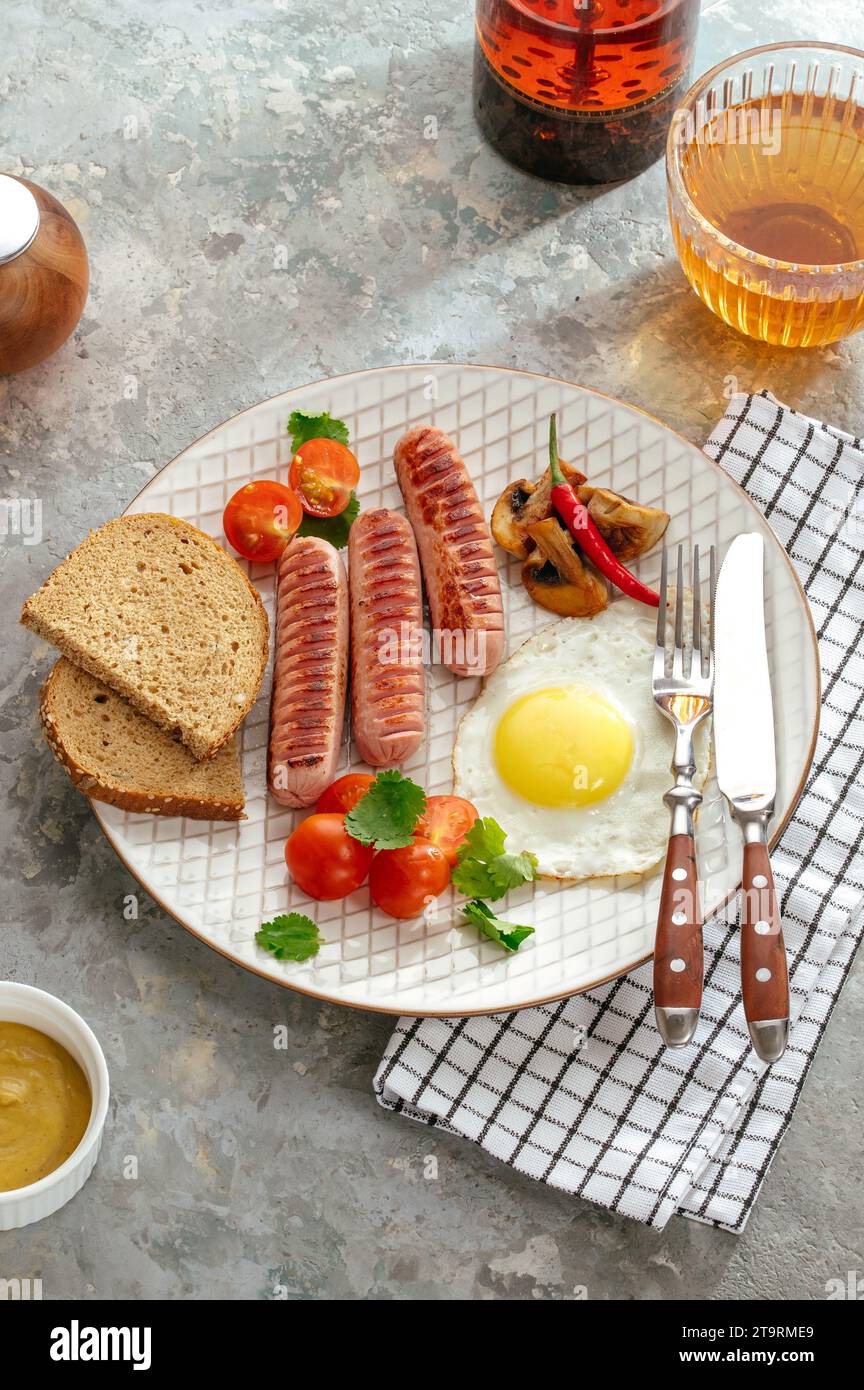 Gegrillte Würstchen mit Sauce und Gemüse auf einem Teller Stockfoto